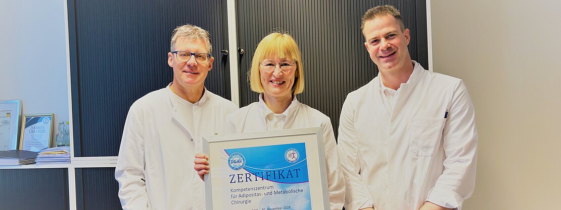 Bild mit Urkunde. Dr. Karin Hüttner, Ärztliche Leiterin des Adipositaszentrums, Dr. Oliver Ponsel, Direktor der Klinik für Allgemein- und Viszeralchirurgie und Oberarzt Dr. (Univ. Niš) Filip Kostic