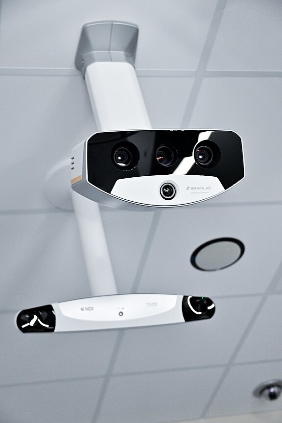 Zwei an der Decke montierte Kamerageräte mit mehreren Linsen und Sensoren, vermutlich für chirurgische Navigation oder Bewegungsverfolgung im Operationssaal.