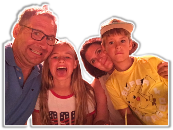 Vier Personen eng beieinander für ein Selfie: ein Mann mit Brille verzieht das Gesicht, ein Mädchen streckt lachend die Zunge raus, eine Frau lächelt dahinter, ein Junge mit Kappe blickt ernst und trägt ein gelbes T‑Shirt mit Pikachu.