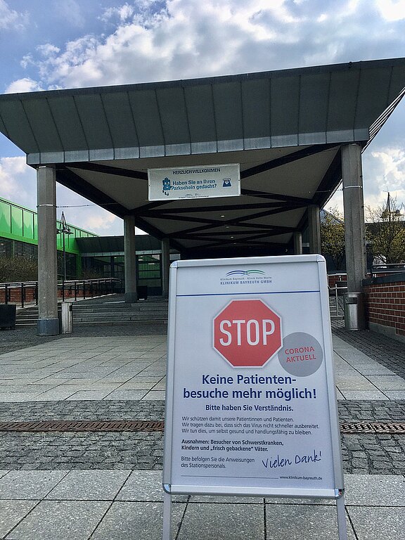 Vor dem Krankenhaus steht ein Aufsteller mit rotem Stoppschild: Wegen Corona sind Patientenbesuche nicht mehr möglich. Besucher werden um Verständnis gebeten.