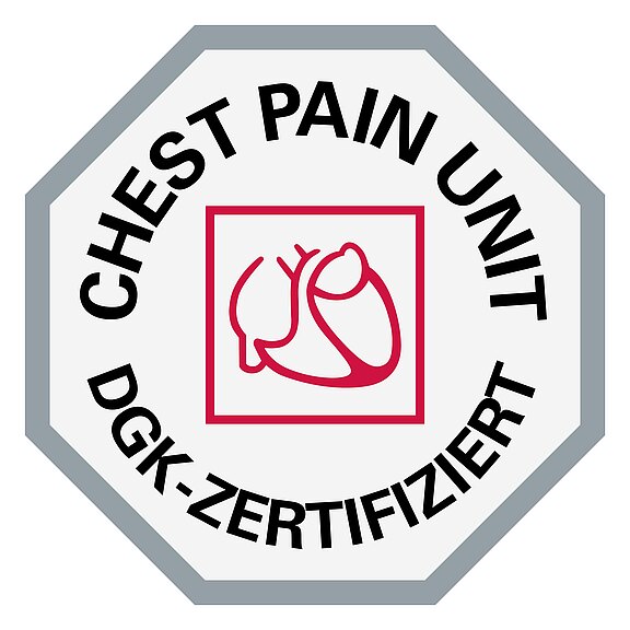 Das Bild zeigt ein sechseckiges Emblem mit der Aufschrift "CHEST PAIN UNIT" und "DGK-ZERTIFIZIERT". In der Mitte befindet sich ein einfaches rotes Symbol eines Herzens. Das Emblem bescheinigt die Zertifizierung eines Brustschmerzzentrums.