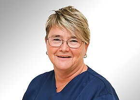 Claudia Igl Porträt einer lächelnden Frau mit kurzem blond-braunem Haar und Brille, in dunkelblauer Berufskleidung vor hellem Hintergrund.