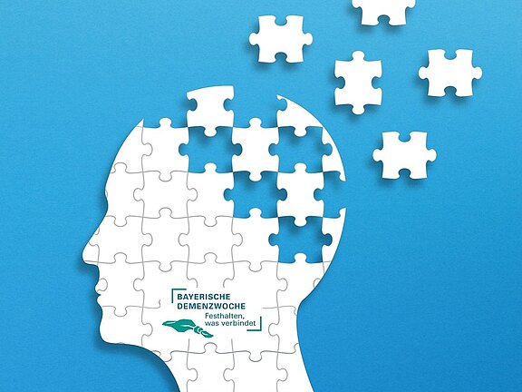 Illustration eines menschlichen Kopfprofils aus weißen Puzzleteilen auf blauem Hintergrund. Oben fehlen Teile und schweben davon – Symbol für Gedächtnisverlust. Im Kopf steht: Bayerische Demenzwoche – Festhalten, was verbindet.