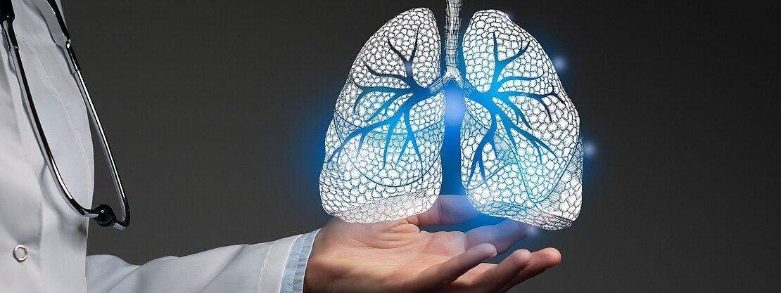 Eine Person im Arztkittel hält eine leuchtende, holografische Darstellung von Lungen mit sichtbaren Bronchien über der geöffneten Hand. Das Motiv symbolisiert Atemwegsdiagnostik, Lungenmedizin oder Gesundheitstechnologie auf dunklem Hintergrund.