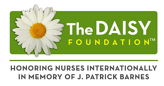 The DAISY Foundation-Logo_INTER Logo der DAISY Foundation: weiße Gänseblume auf grünem Hintergrund; Schriftzug „The DAISY Foundation“. Zusatz: Würdigung von Pflegekräften weltweit zum Gedenken an J. Patrick Barnes.