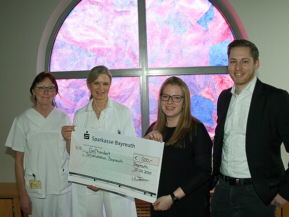 Vier Personen, zwei in weißer Klinikbekleidung, zwei in Zivil, halten gemeinsam einen übergroßen Spendenscheck der Sparkasse Bayreuth über 500 Euro für die Palliativstation Bayreuth, datiert 30.01.2020.