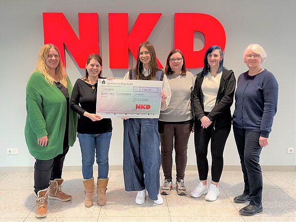 Auszubildende von NKD überrechen einen Spendenscheck an Barbara Koch